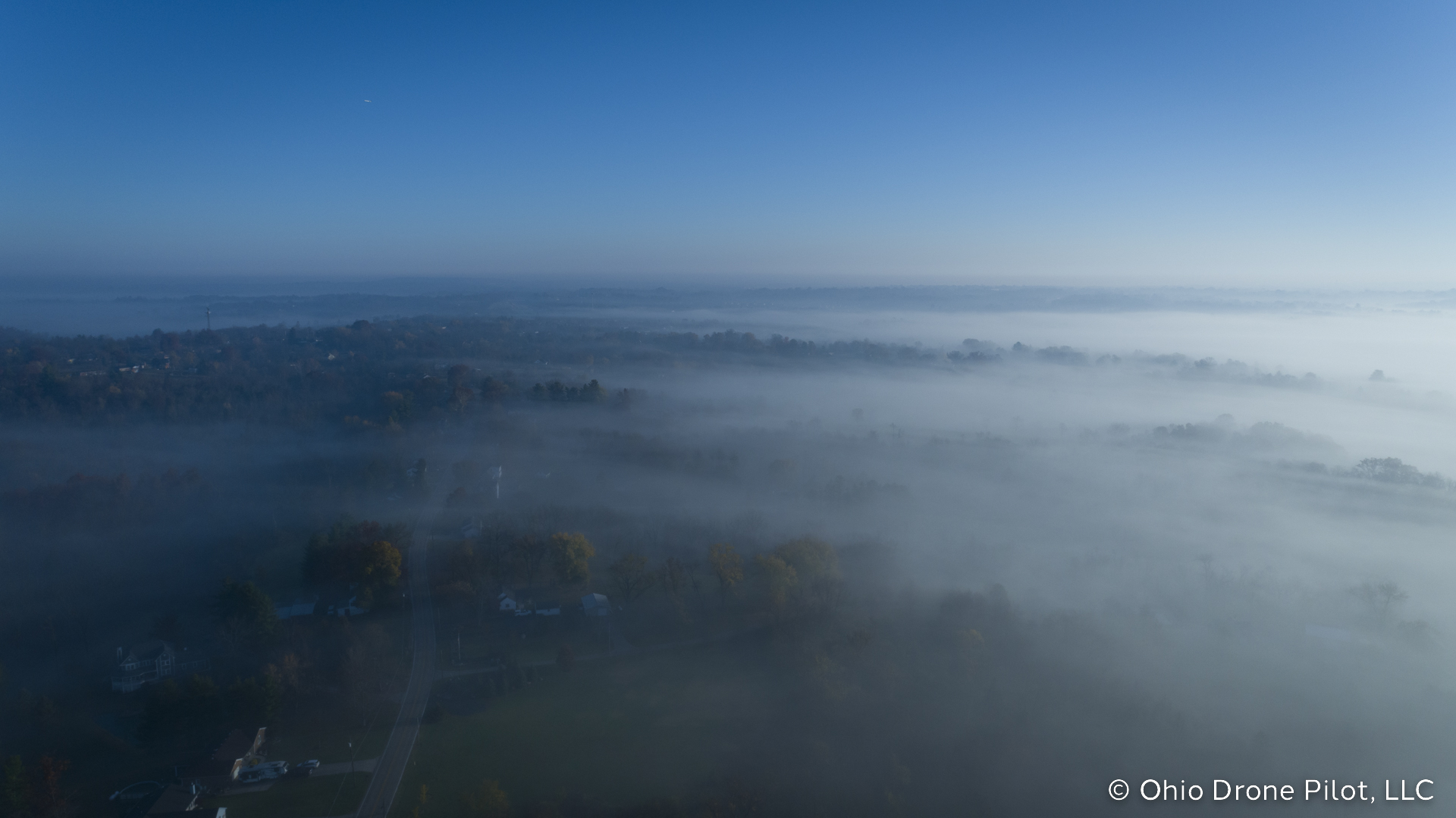 Aerial view of fog rolling across a tree-covered ridge