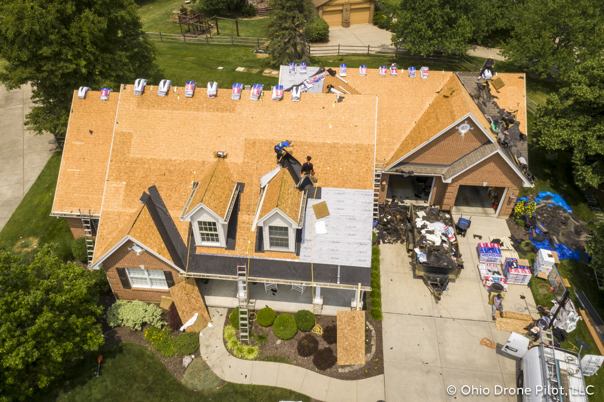 In-progress, aerial view of a roof replacement. Most of the shingles have been removed and workers are preparing the roof deck. Photography by Ohio Drone Pilot, LLC.