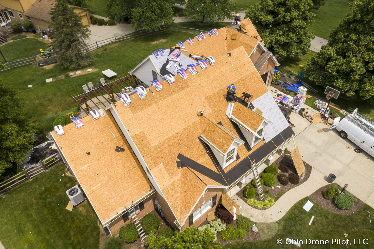 In-progress, aerial view of a roof replacement. Most of the shingles have been removed and workers are preparing the roof deck. Photography by Ohio Drone Pilot, LLC.