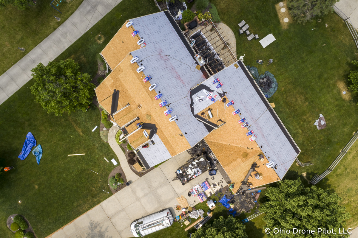 In-progress, aerial view of a roof replacement. Most of the shingles have been removed and workers are preparing the roof deck. Photography by Ohio Drone Pilot, LLC.