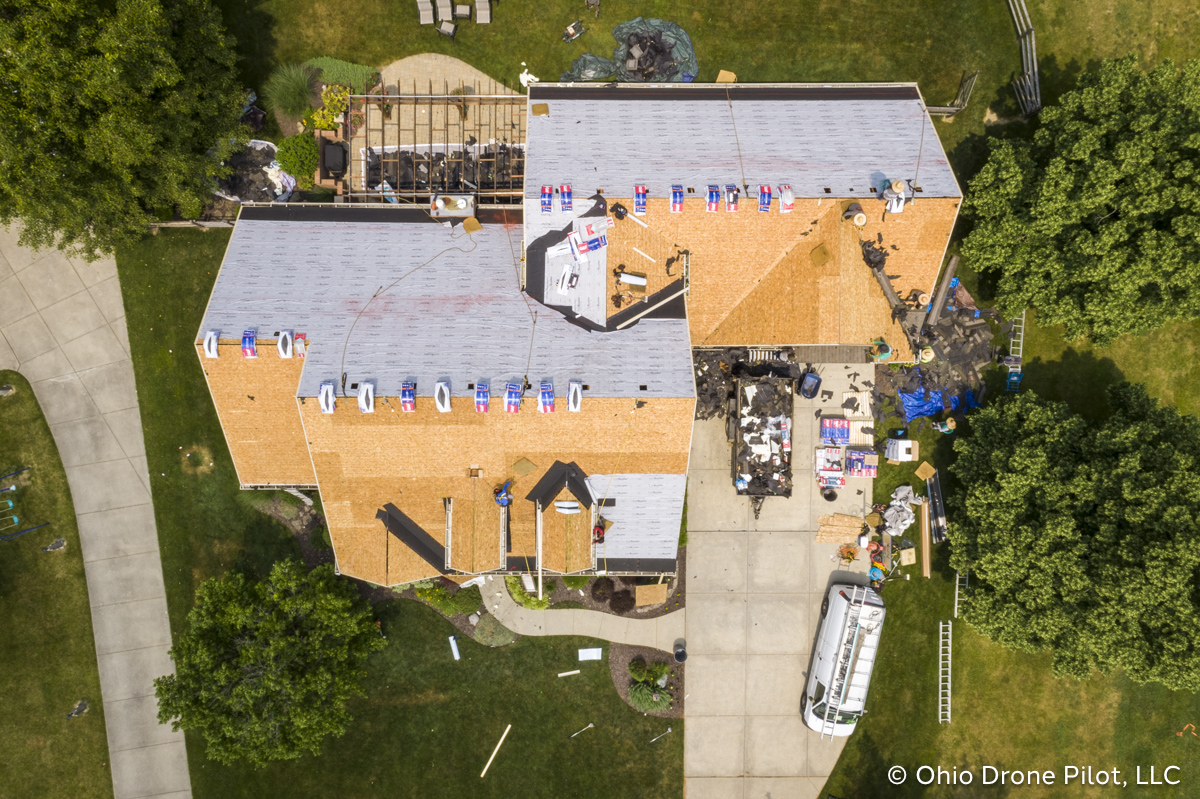 In-progress, aerial view of a roof replacement. Most of the shingles have been removed and workers are preparing the roof deck. Photography by Ohio Drone Pilot, LLC.