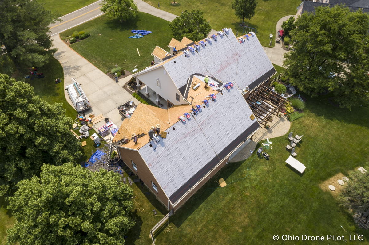 In-progress, aerial view of a roof replacement. Most of the shingles have been removed and workers are preparing the roof deck. Photography by Ohio Drone Pilot, LLC.