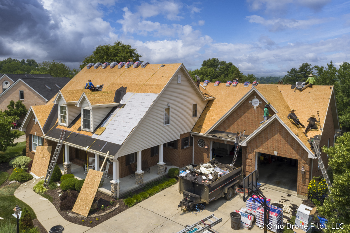 In-progress, aerial view of a roof replacement. Most of the shingles have been removed and workers are preparing the roof deck. Photography by Ohio Drone Pilot, LLC.